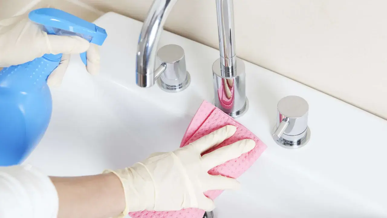 Mit Handschuhen und einem selbstgemachten Badreiniger wird das Waschbecken blitzblank.