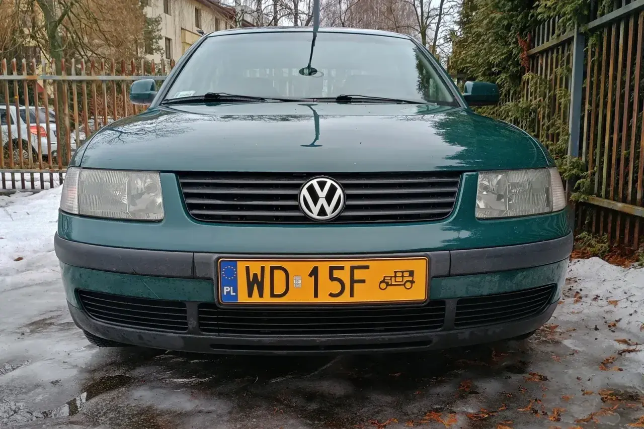 Zielony samochód zabytkowy, może 25 czy 30 lat, z charakterystycznym znaczkiem VW na grillu, stoi na oblodzonym podjeździe.