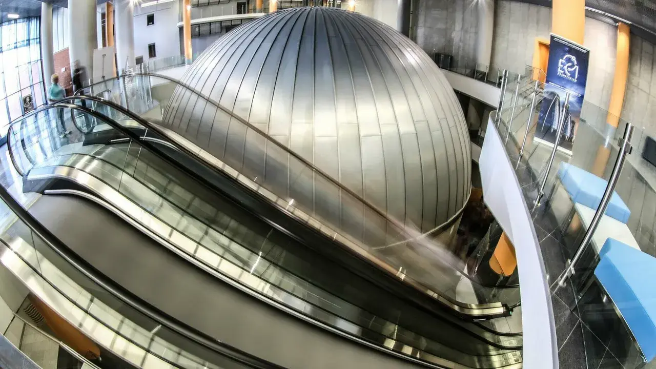 Nowoczesne wnętrze z kopułą i ruchomymi schodami. EC1 Planetarium to miejsce, które warto zobaczyć, pełne naukowych atrakcji.