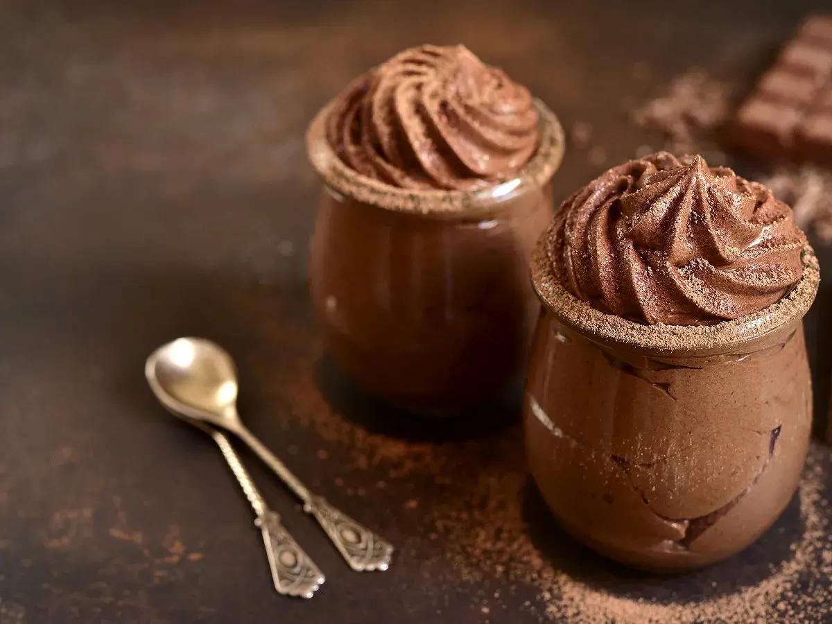 Délicieuse présentation de mousse au chocolat, garnie de cacao, prête à être dégustée avec des cuillères élégantes.