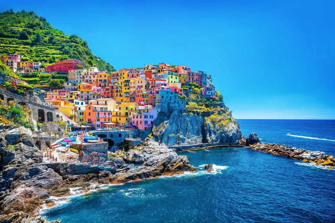 Village coloré accroché à la falaise, vue sur la mer bleue. Un gîte Cinque Terre parfait pour des vacances inoubliables.