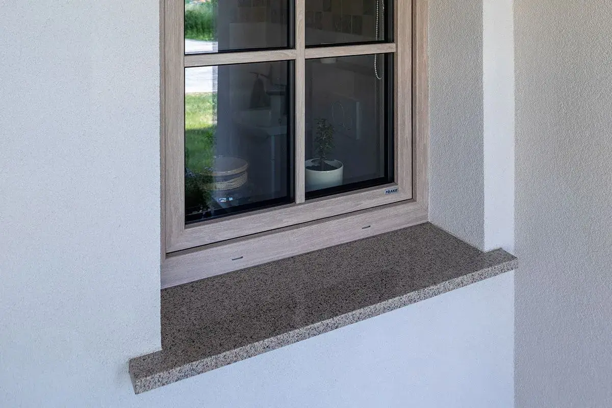 Granitowy parapet zewnętrzny wystaje ok. 5 cm, chroniąc elewację. Idealna proporcja, by wiedzieć, ile powinien wystawać parapet zewnętrzny.