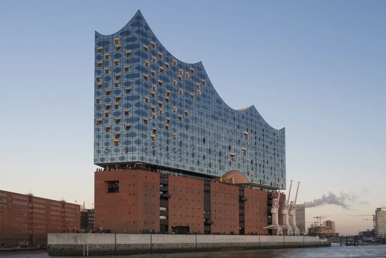 Elbphilharmonie Hamburg mit Glasfassade und Backsteinsockel am Wasser.