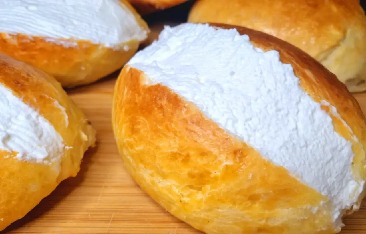 Maritozzi ricetta originale: soffici panini dolci farciti con abbondante panna montata, pronti per essere gustati.