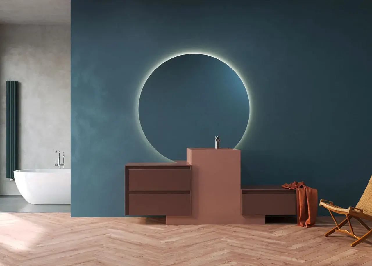 Mobile bagno moderno con lavabo integrato in materiale corian, specchio circolare retroilluminato e finiture in legno.