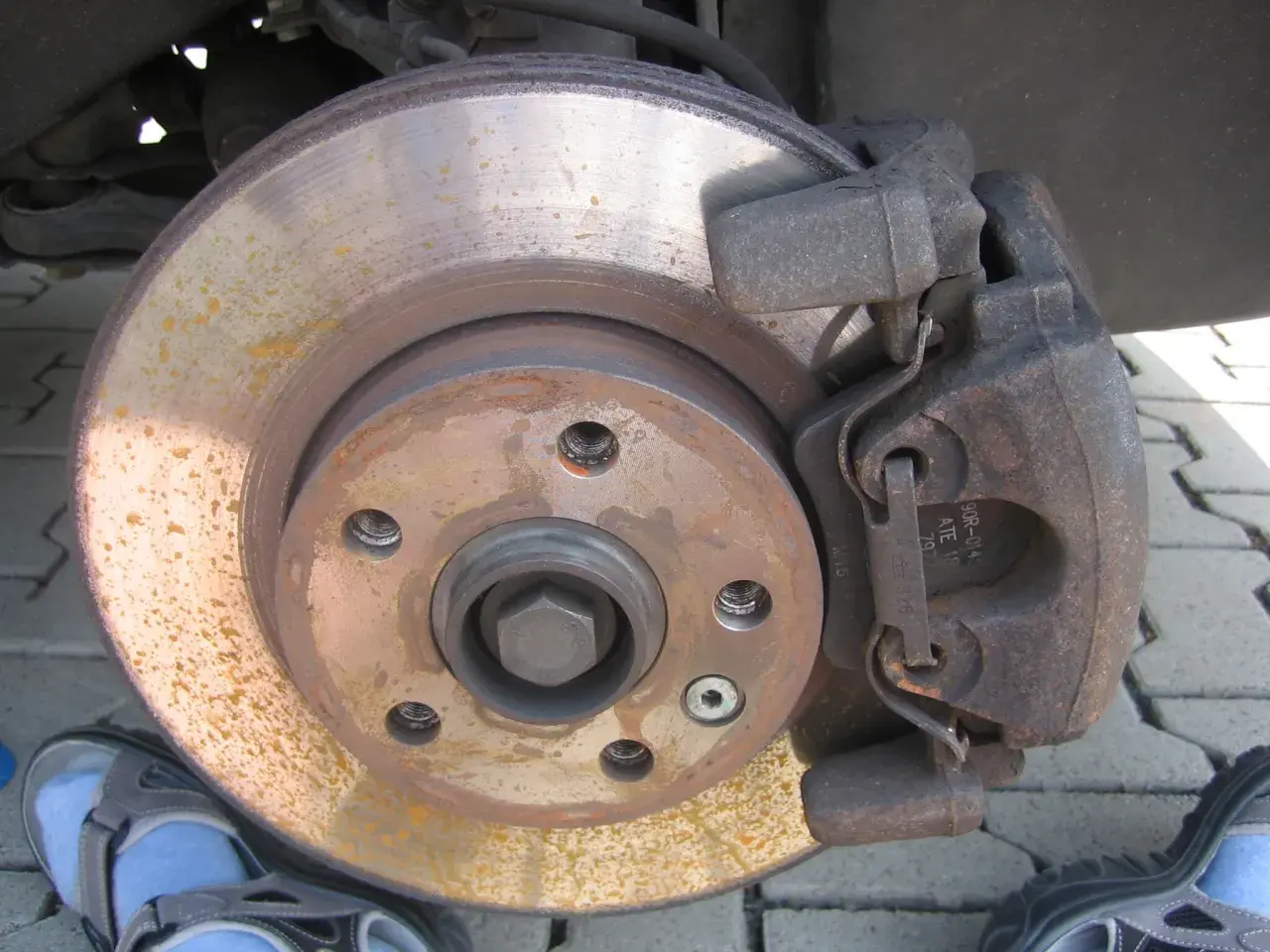 Bremsbeläge und Bremsscheibe zeigen Rostspuren. Das Auto klackert beim Bremsen, was auf Verschleiß hindeutet.