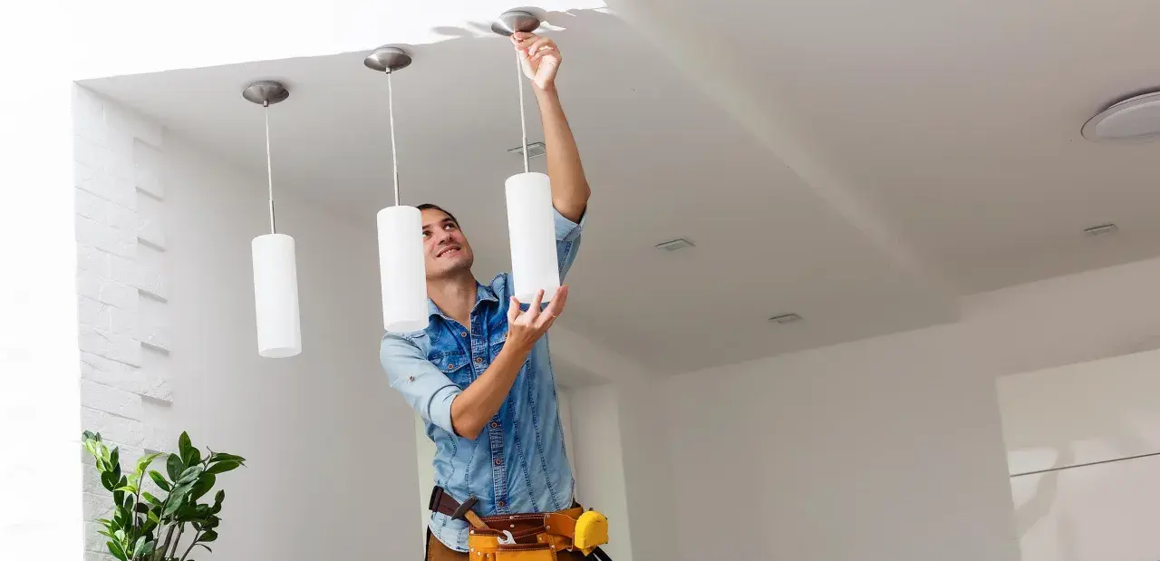 Hombre instalando una lámpara de techo. Aprende como cambiar una lámpara de techo fácilmente.