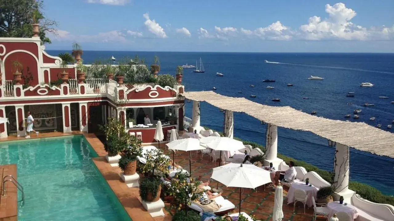 Terraza del Hotel Europa con piscina, tumbonas y vistas al mar azul con barcos.