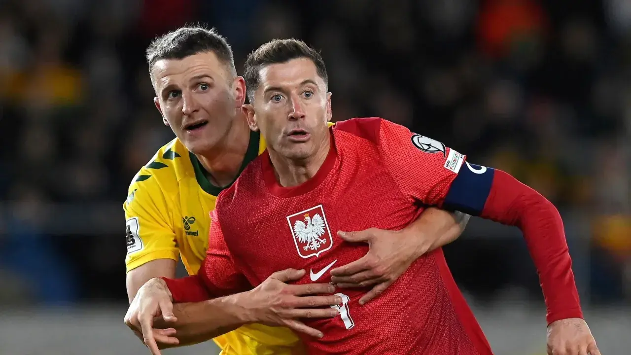 Robert Lewandowski, kapitan Polski, w czerwonej koszulce z orłem, walczy o piłkę z przeciwnikiem.