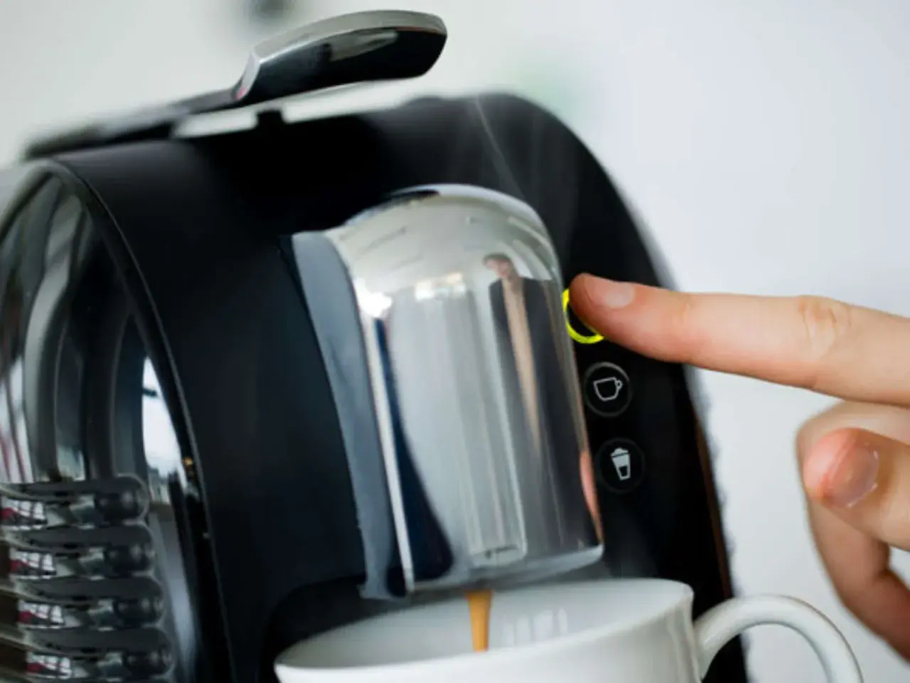 Finger drückt Knopf an Kaffeemaschine. Zeit, den Kaffeeautomaten zu entkalken für perfekten Kaffeegenuss.