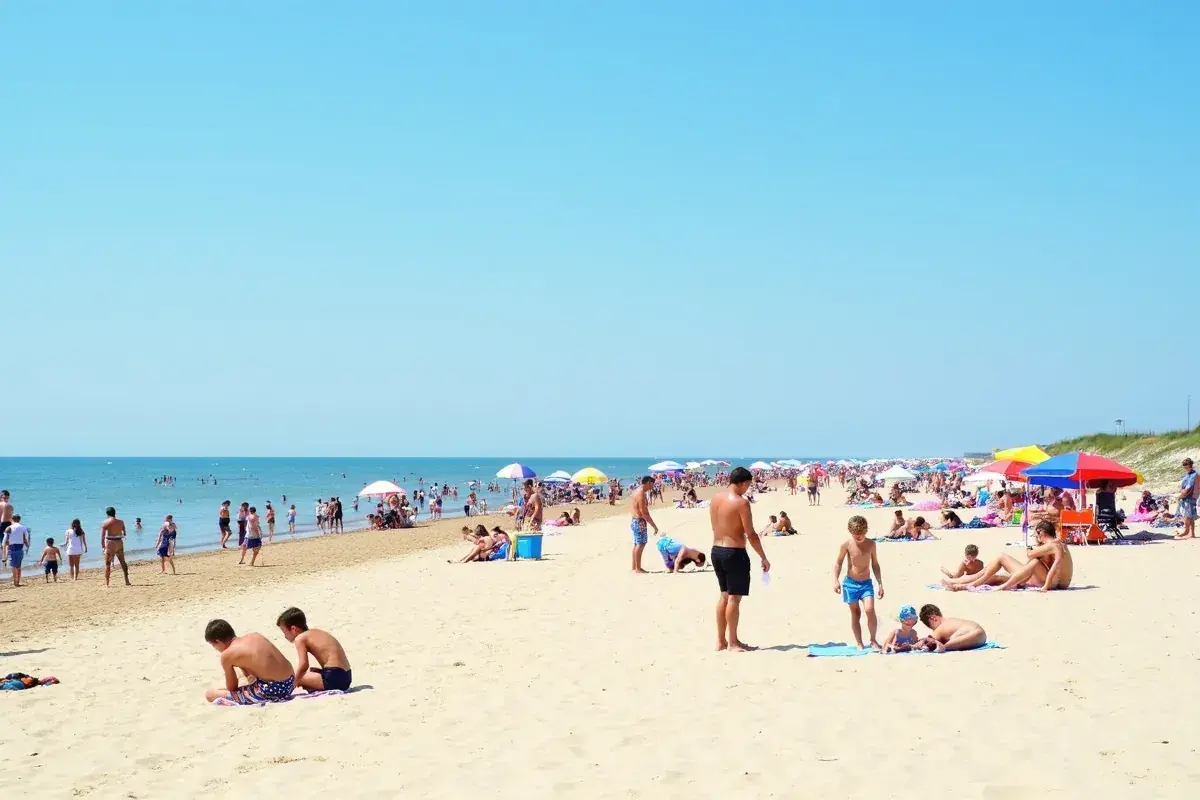 Tłum ludzi na piaszczystej plaży, szukających odpowiedzi na pytanie: gdzie najbliżej nad morze z Warszawy.