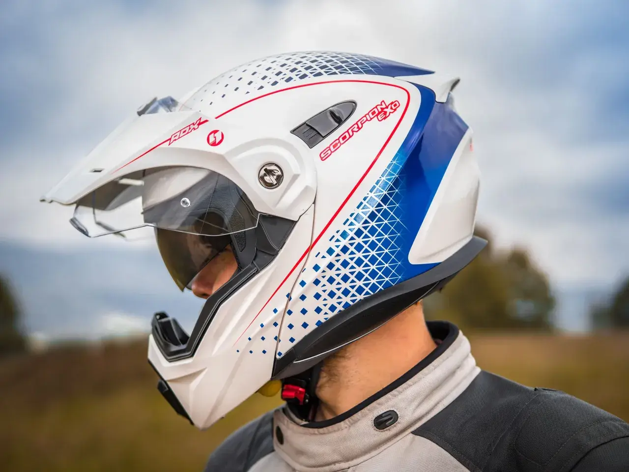 Biały kask motocyklowy Scorpion EXO z niebieskimi i czerwonymi detalami, zapięcie DD.