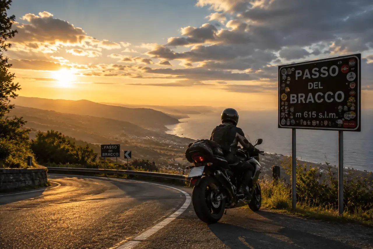 Motociclista ammira il tramonto sulle **strade panoramiche Liguria in moto**. Segnale del Passo del Bracco.