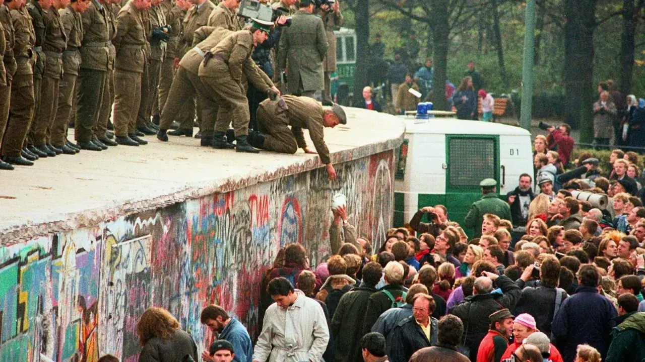 Menschen feiern die Wiedervereinigung Deutschlands am Berliner Mauer. Soldaten helfen Menschen über die Mauer. Eine Zusammenfassung der Freude und des Wandels.