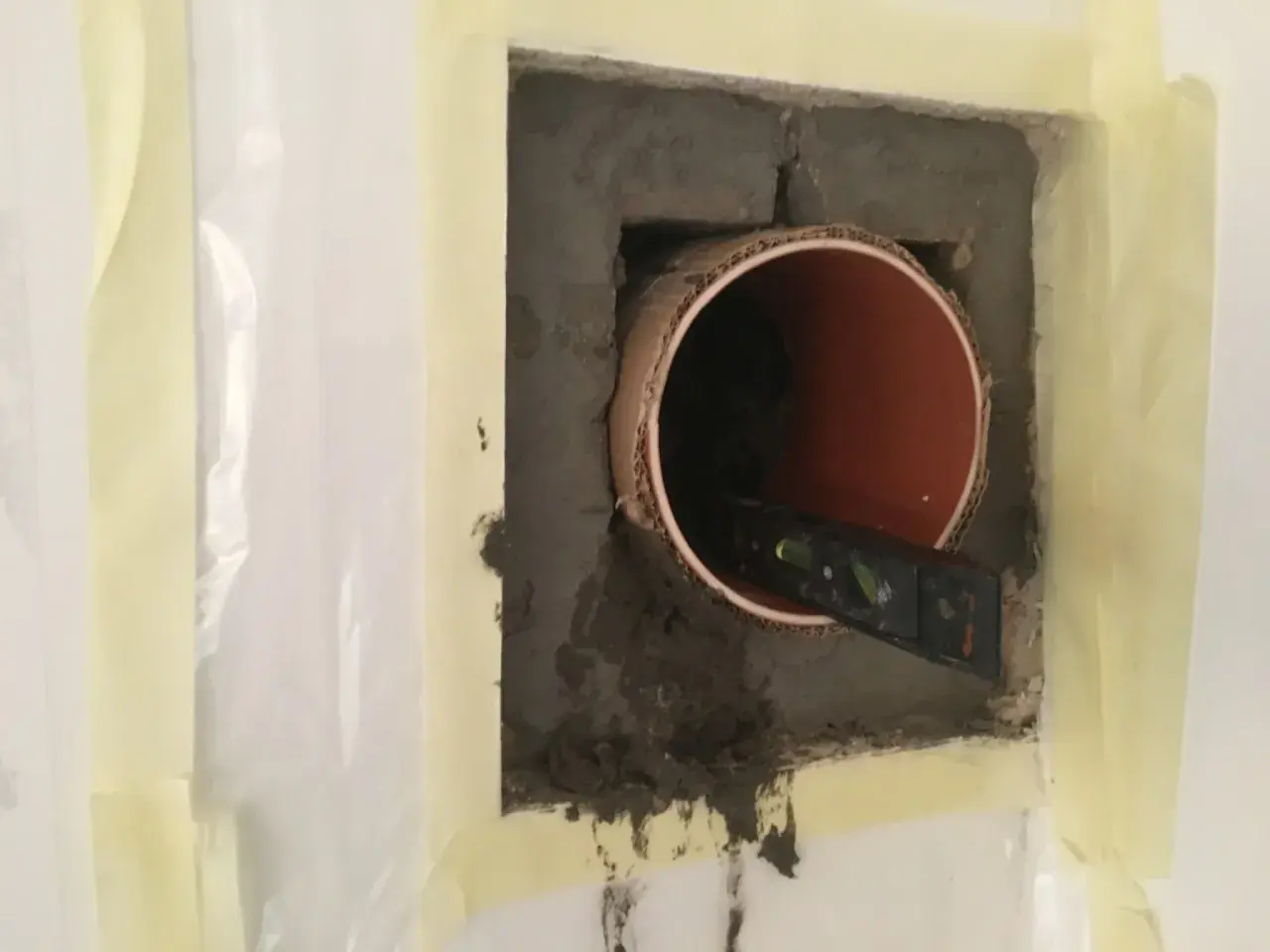 Inmurningsstos montering. Ett rör sitter i en betongvägg, en vattenpass kontrollerar att det är rakt.