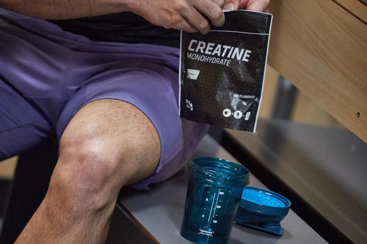 Kreatyna monohydrat - co daje przedtreningówka? Worek z kreatyną i shaker czekają na trening.