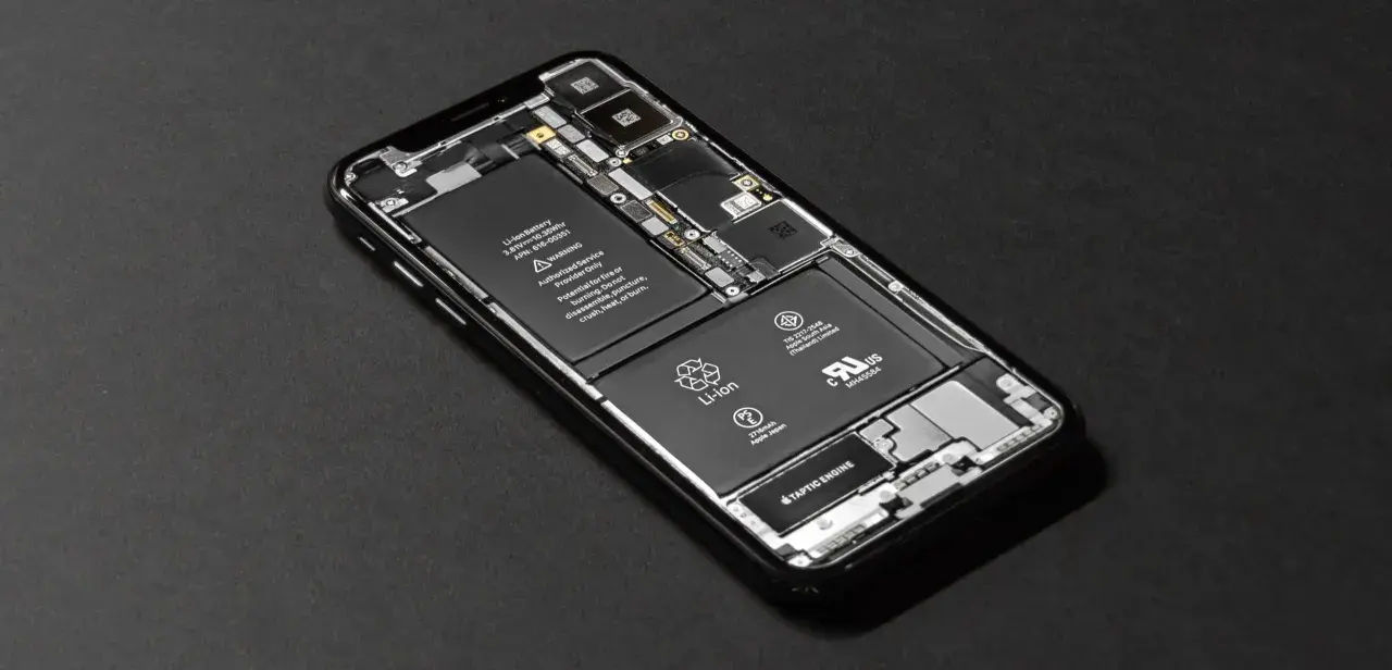 Rozłożony iPhone SE z widoczną baterią i podzespołami.