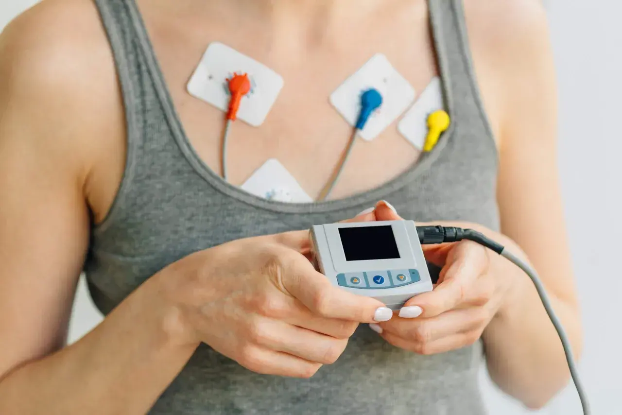 Kobieta z elektrodami na klatce piersiowej i małym urządzeniem do monitorowania EKG. Przygotowanie do badania EKG.