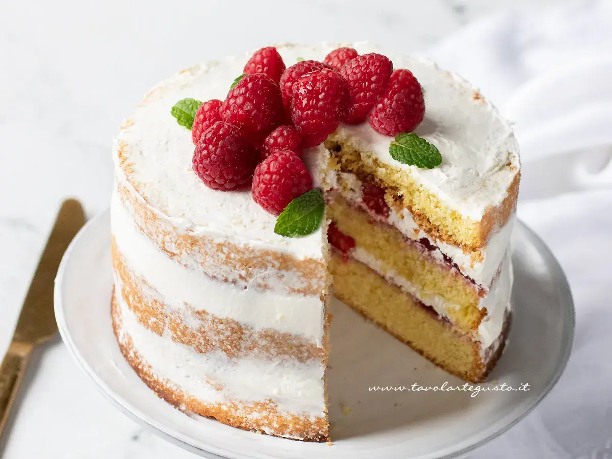 Deliziosa torta di buon compleanno a strati, ricoperta di panna e decorata con lamponi freschi e foglie di menta.