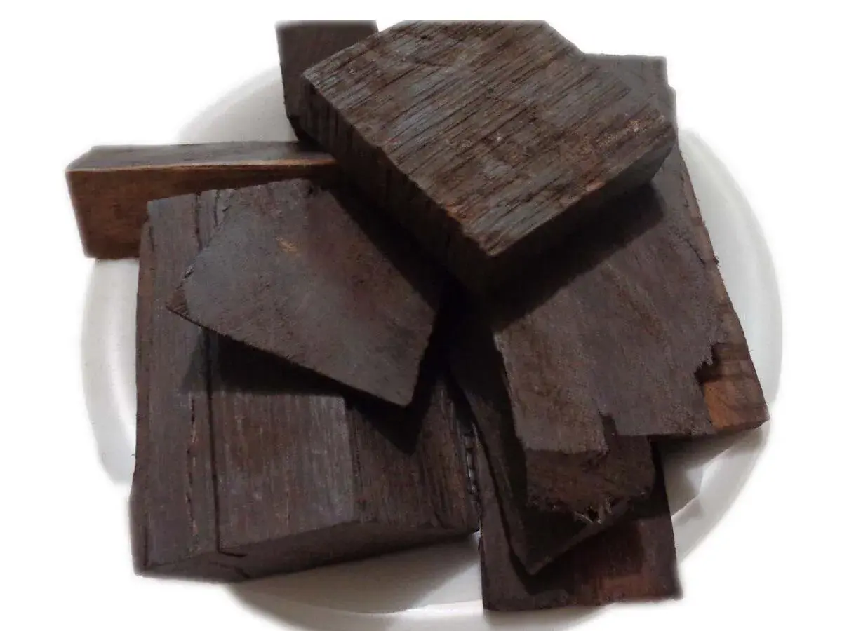 Pezzi di legno scuro, forse ebano, il legno più costoso del mondo, su un piatto bianco.