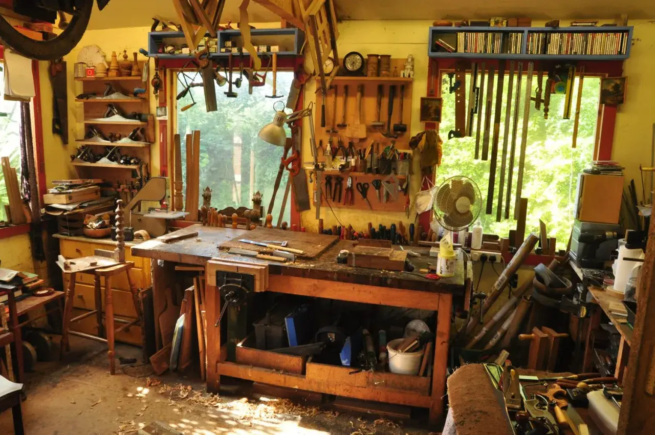 Un laboratorio pieno di attrezzi mostra come si lavora il legno: pialle, seghe, scalpelli e un banco da lavoro pronto per creare.