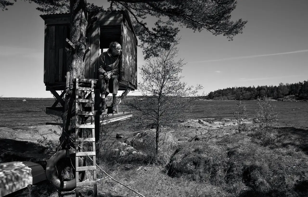 Man i trädkoja vid havet, som hämtad ur en berättelse av John Ajvide Lindqvist. Barnens lekplats blir en plats för eftertanke.
