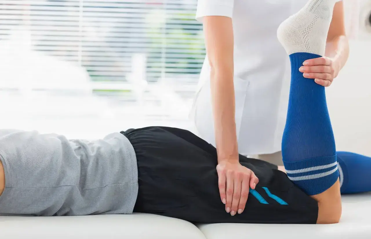 Un physiothérapeute aide un patient à étirer sa jambe pour soulager une crampe cuisse.