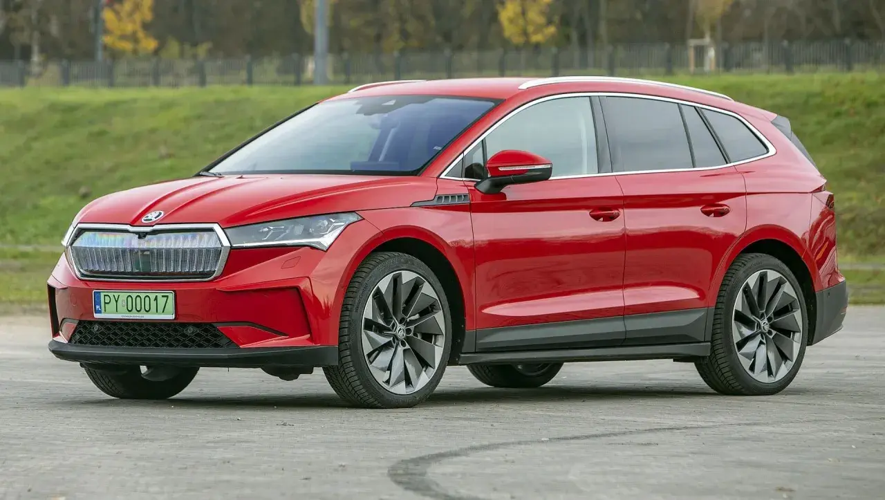 Czerwona Skoda Enyaq na tle zieleni. Sprawdź aktualną skoda enyaq cena i wybierz swój wymarzony samochód elektryczny.