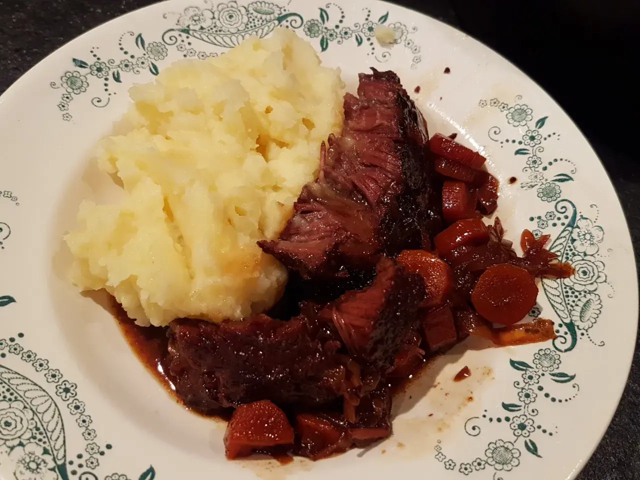 Un plat réconfortant de joue de bœuf à la bière, tendre et savoureuse, accompagnée d'une purée de pommes de terre onctueuse.