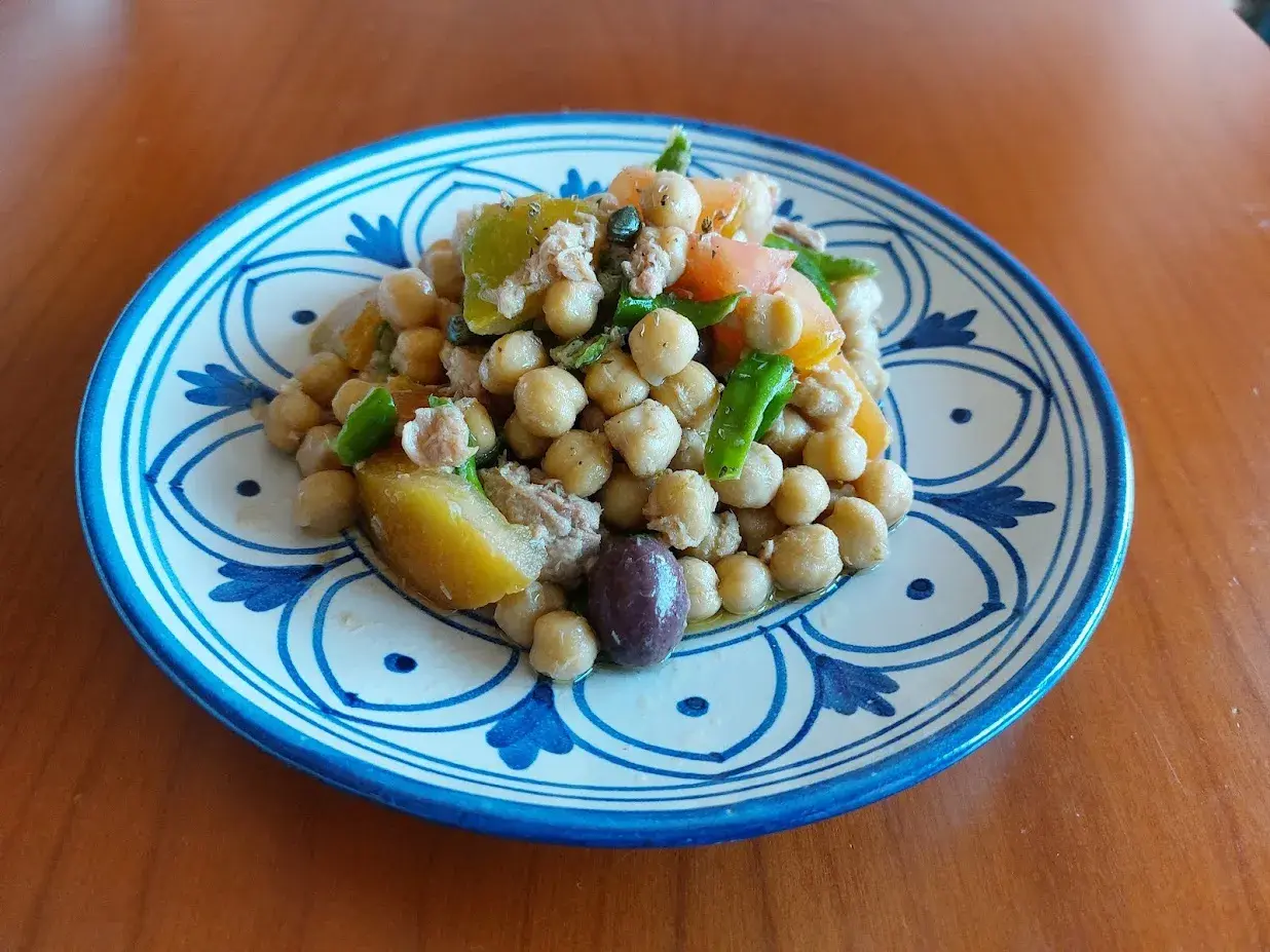 Un'appetitosa insalata di ceci alla siciliana, con pomodoro, olive e verdure fresche, servita su un piatto decorato.