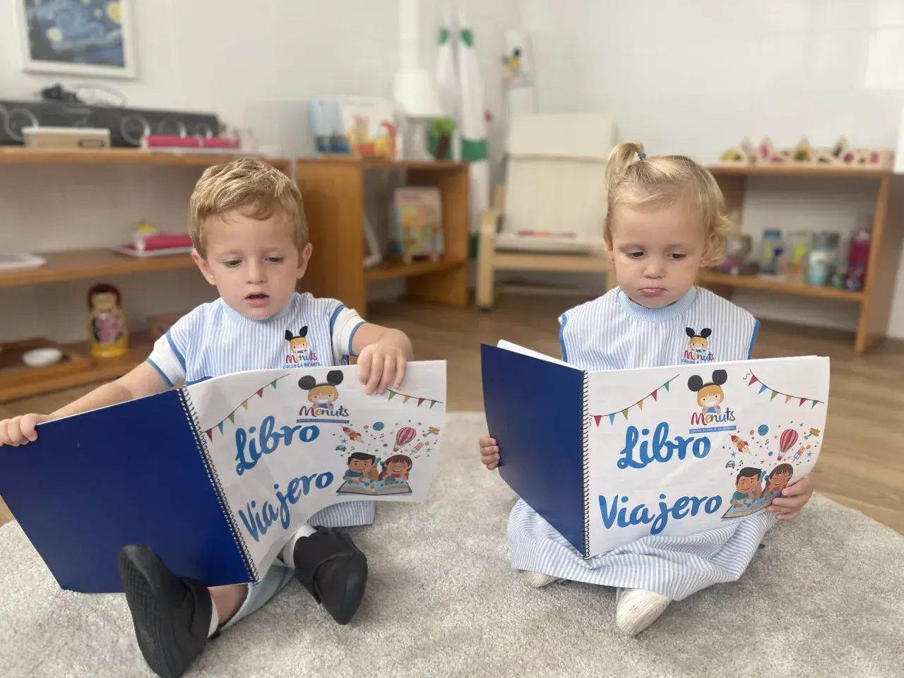Niños leyendo un libro viajero infantil, con dibujos de cohetes y globos aerostáticos.