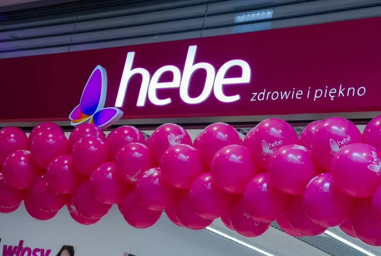 Logo Hebe z motylem i girlanda różowych balonów.