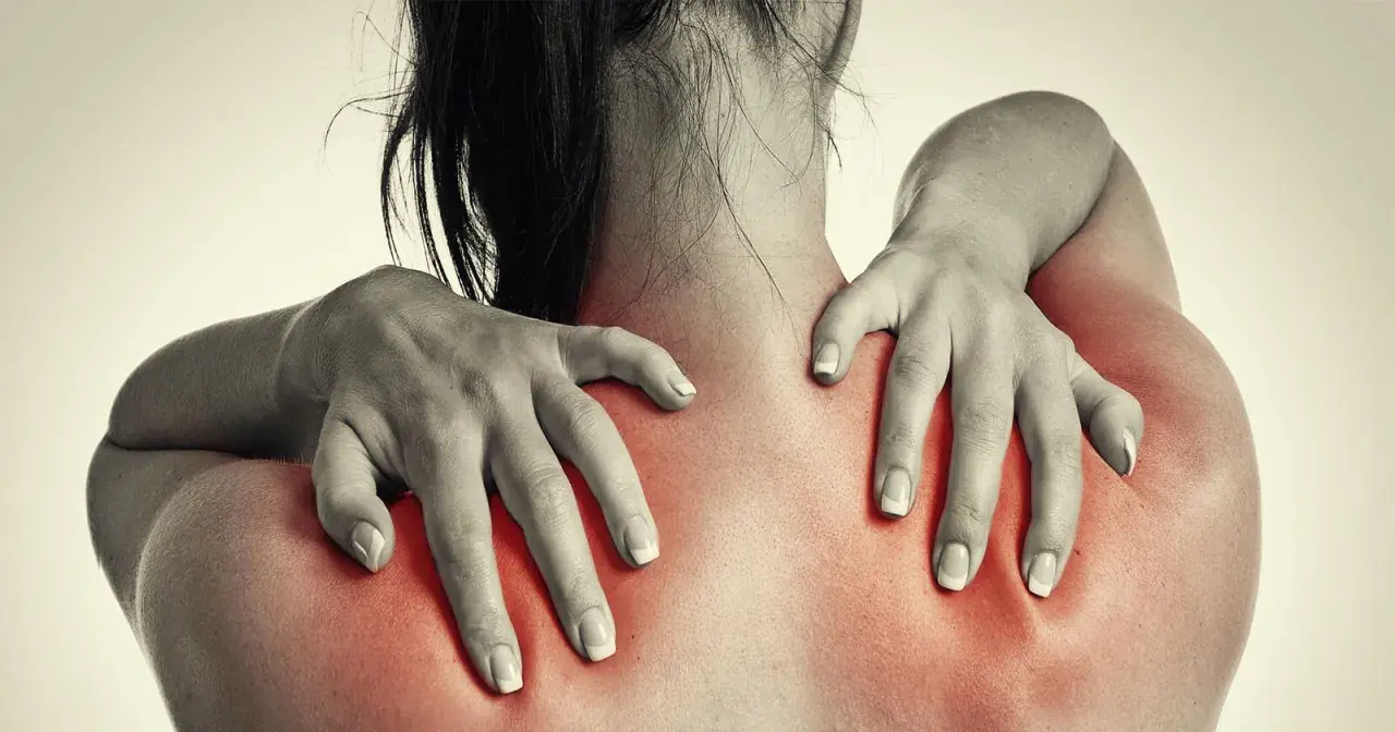 Frauenhände massieren schmerzende Schultern, die rot aufleuchten. Magnesium kann bei Hexenschuss Linderung verschaffen.