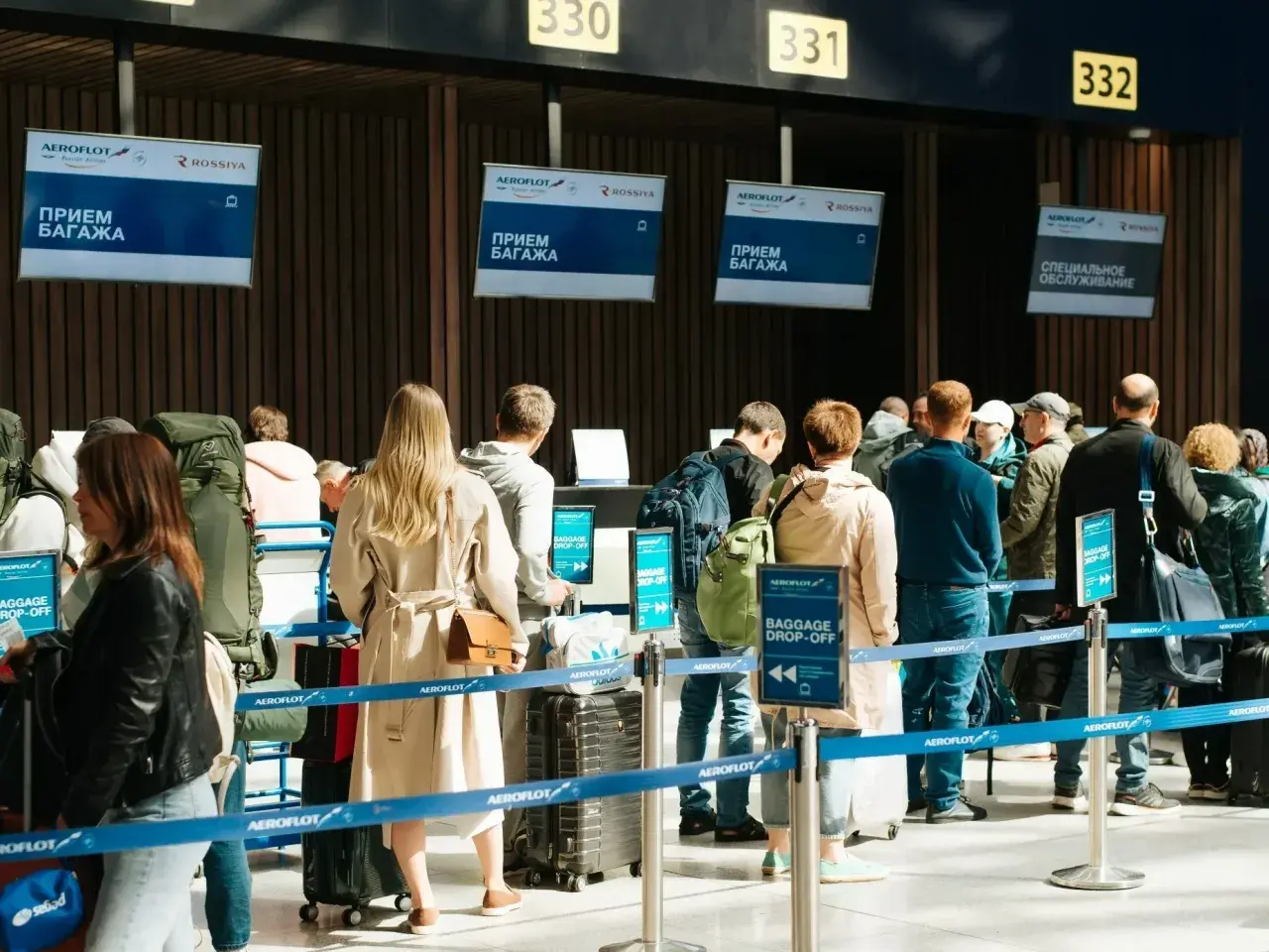 Kolejka do odprawy bagażowej. Na ekranach widnieje napis "BAGGAGE DROP-OFF", ale nie ma żadnego "no show".