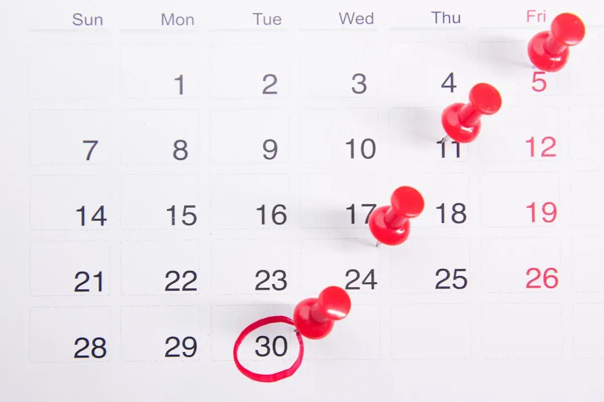 Un calendrier avec des punaises rouges marquant des dates importantes, dont le 30, soulignant le **délai de forclusion**.