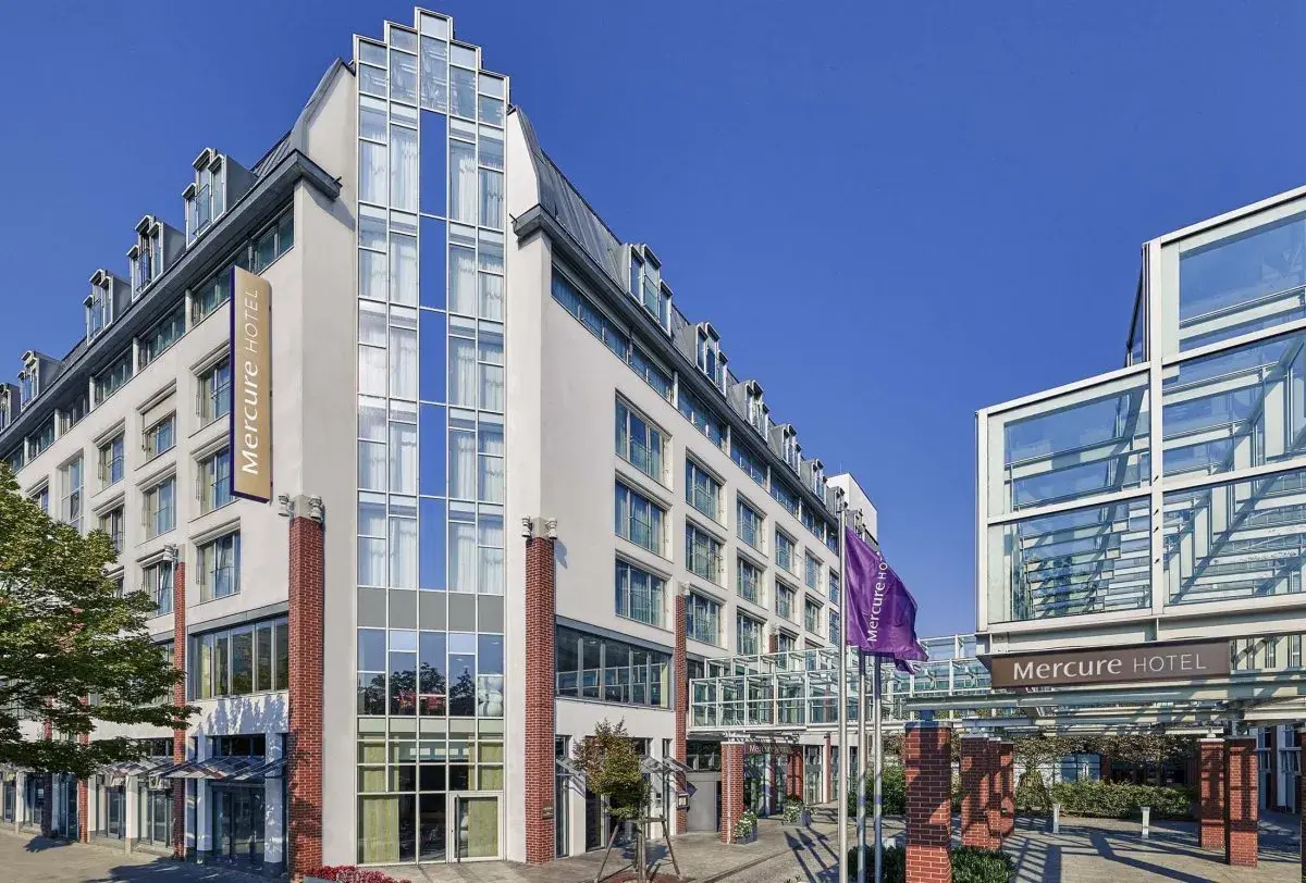 Mercure Hotel Berlin Tempelhof: moderne Fassade mit Glas und Ziegelsteinen, Flagge und Eingangsbereich.