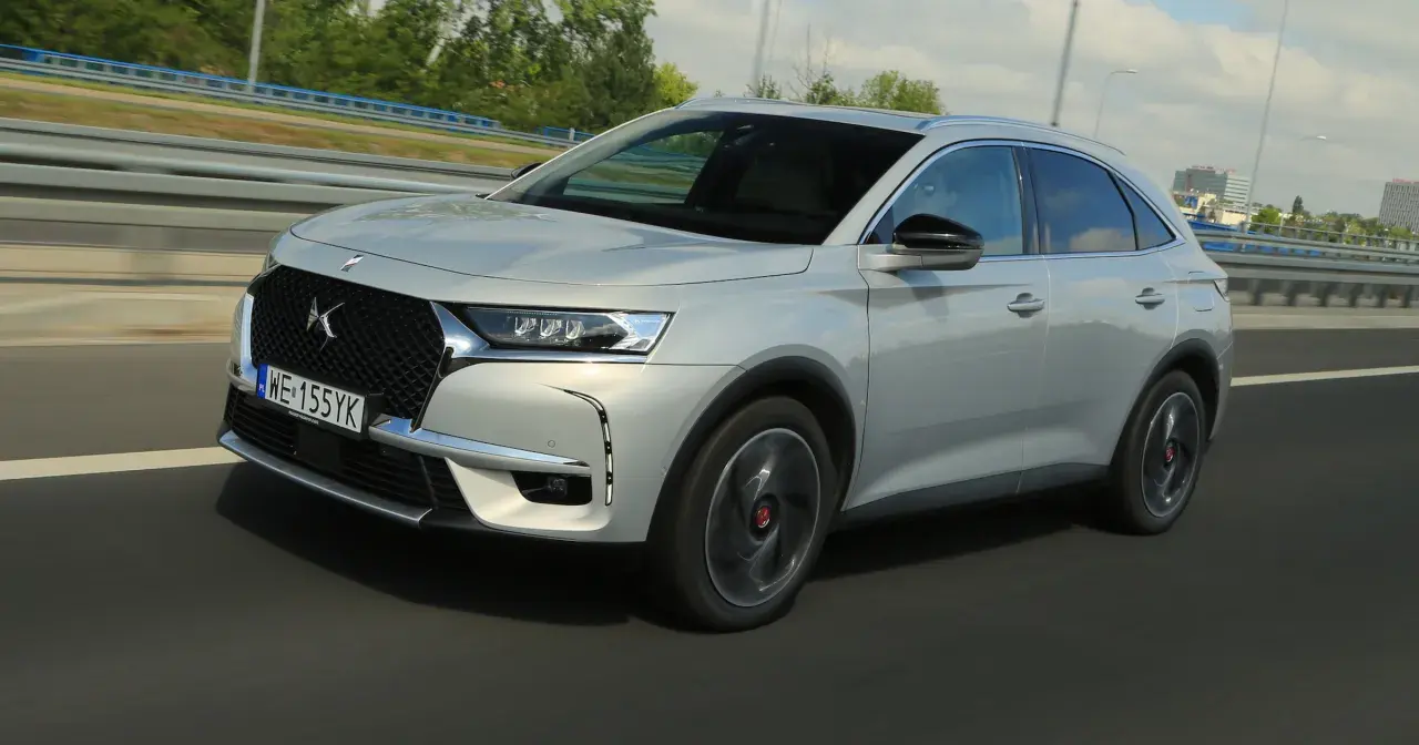 Srebrny DS 7 Crossback E-Tense pędzi autostradą, jego elegancka linia podkreślona przez dynamiczne światła.