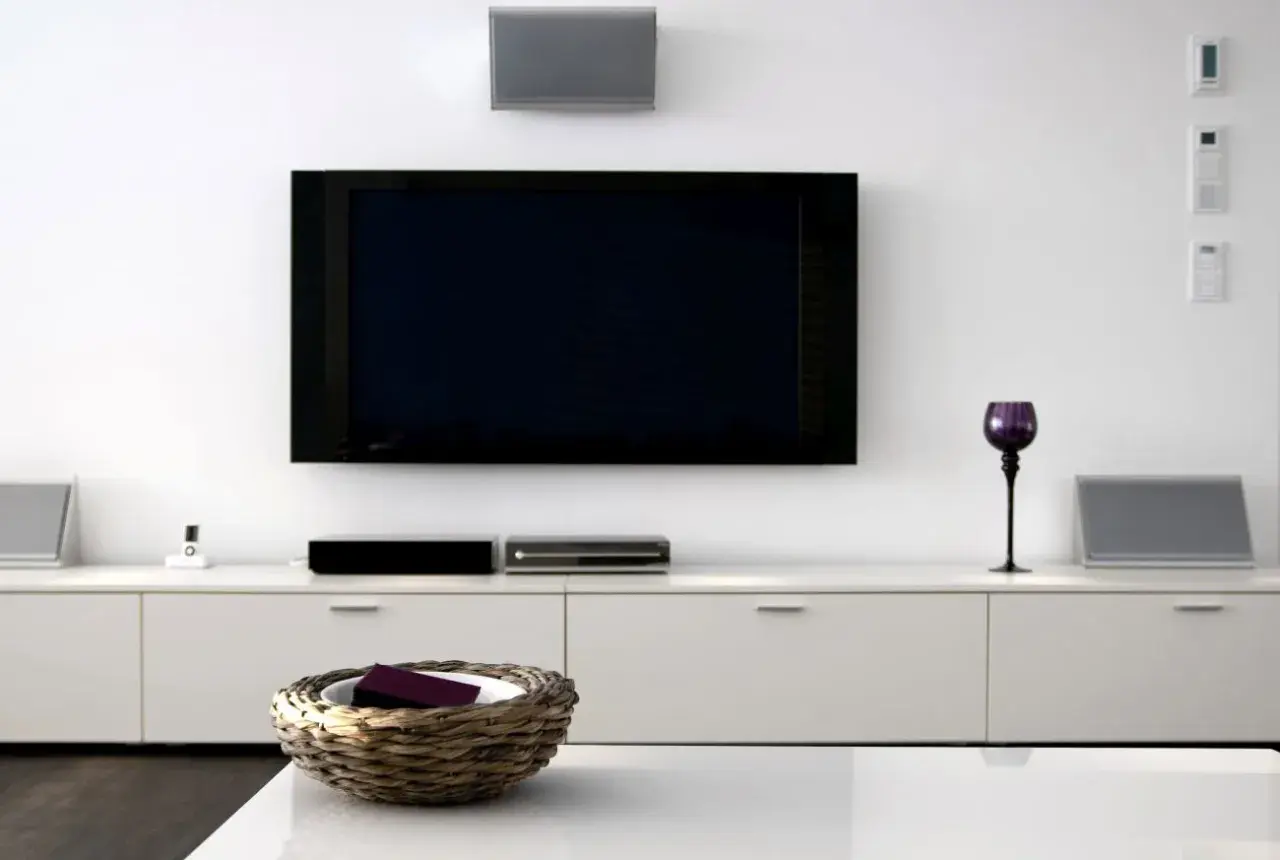 Nowoczesny salon z dużym telewizorem na ścianie, białymi meblami i dekoracjami.