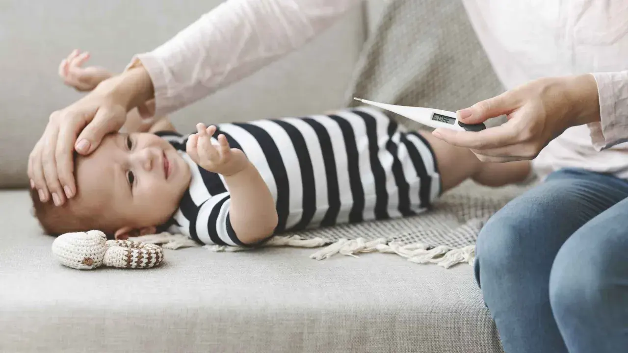 Mamma controlla la febbre al neonato di 1 mese con un termometro. 38.0°C.