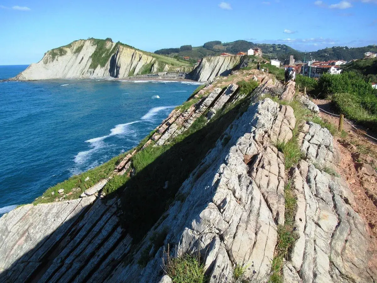 Acantilados vascos, como los de "Ocho Apellidos Vascos", con el mar azul y un sendero rocoso.