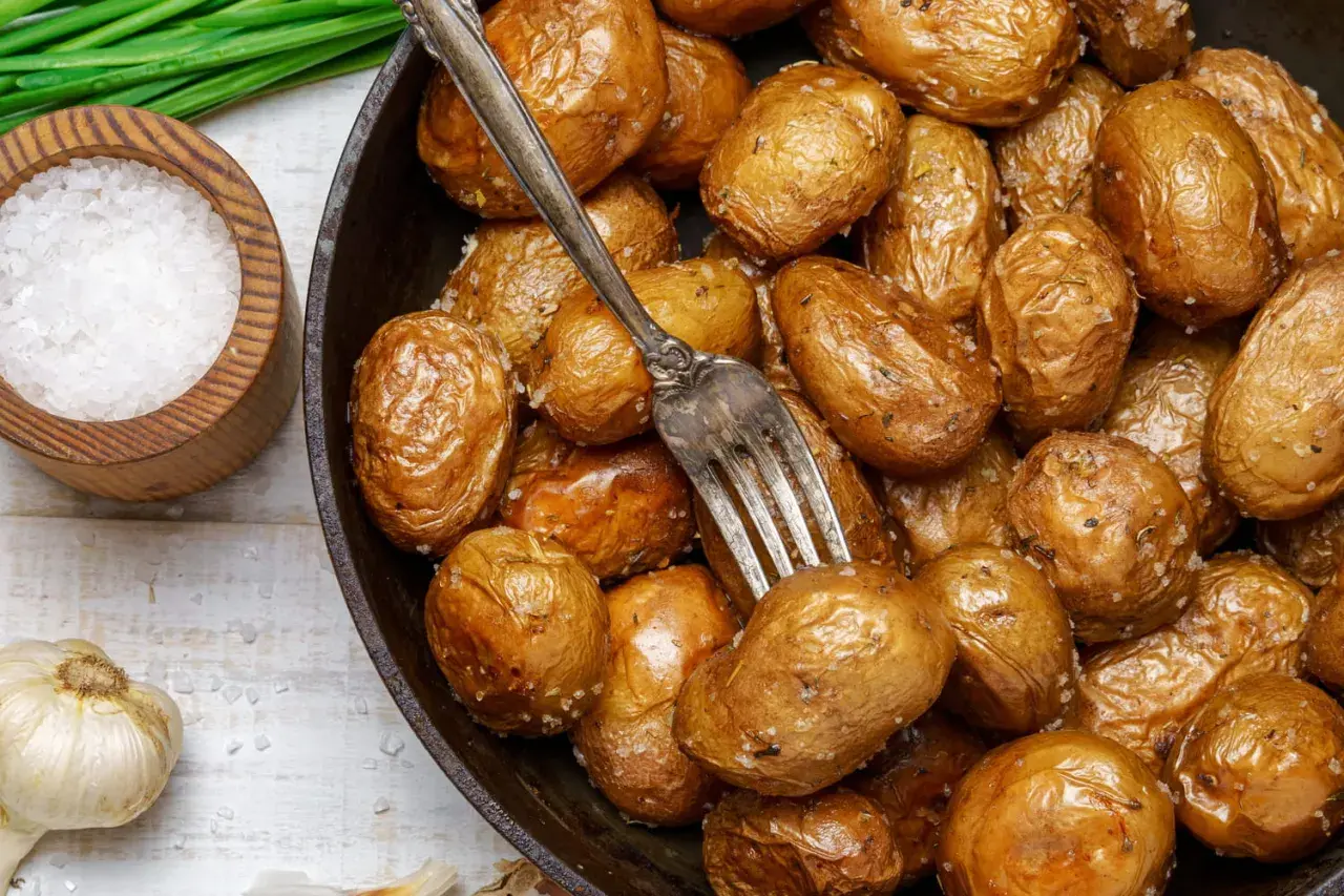 Pommes de terre grenaille dorées et croustillantes, tout juste sorties de l'airfryer. Une fourchette est plantée dans ce délice salé.