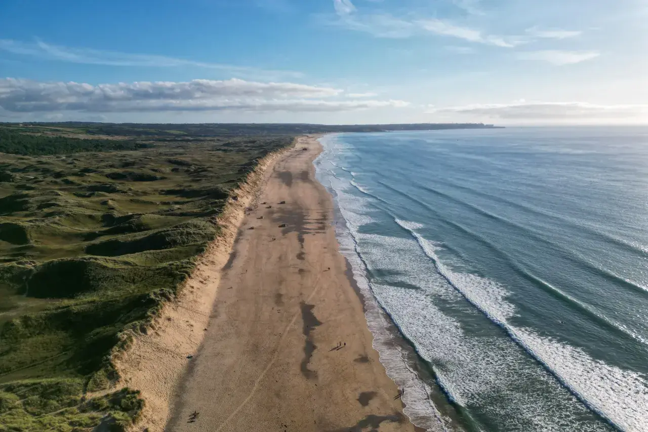 Weite Sandstrände und sanfte Dünen, ideal für mai reiseziele. Die Wellen des Ozeans laden zum Surfen ein.