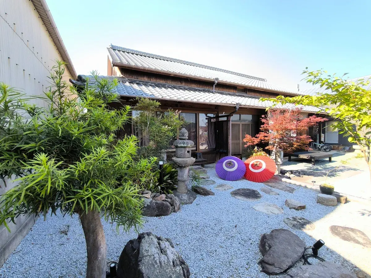 Tradycyjny dom na wyspie Japonii z Kagawa, z kamiennym ogrodem, parasolami i jesiennym drzewem klonowym.