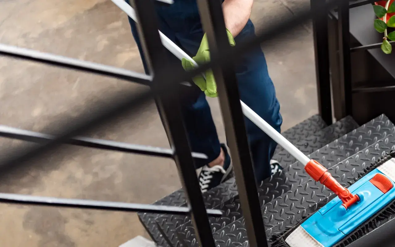 Person reinigt Treppe mit Mopp. Dies kann durch den **Entlastungsbetrag Haushaltshilfe** finanziert werden.