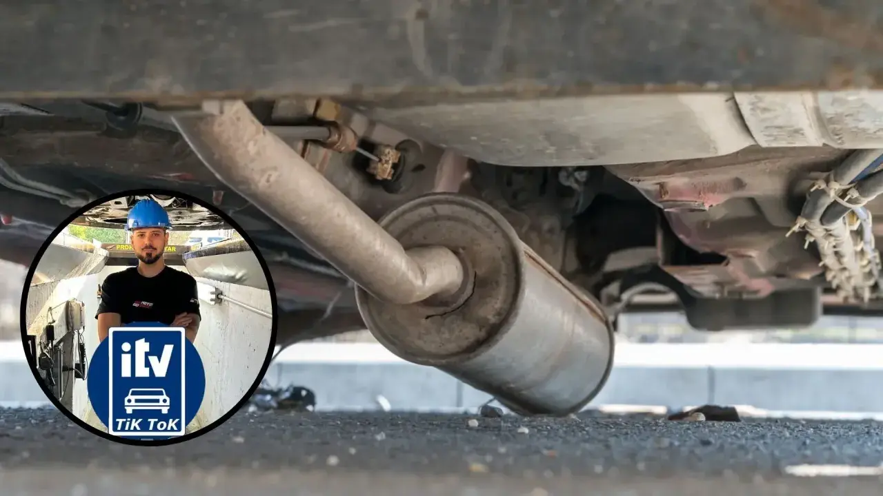Inspección del tubo de escape de un coche. Un mecánico con casco azul supervisa la revisión.