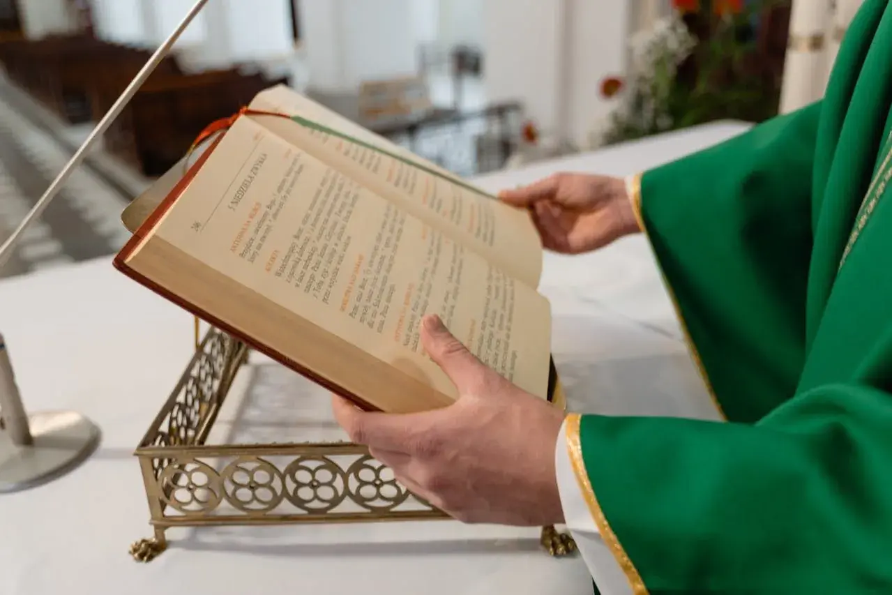 Kapłan w zielonej szacie czyta z księgi liturgicznej. Zastanawiasz się, ile trwa msza niedzielna?