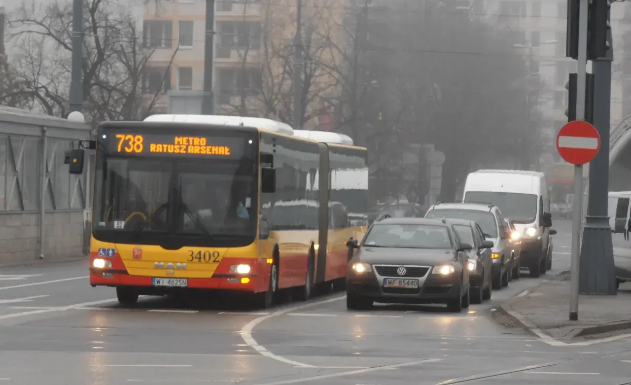 Autobus linii 738 z napisem "METRO RATUSZ ARSENAŁ" w ruchu miejskim, w tle samochody i budynki.