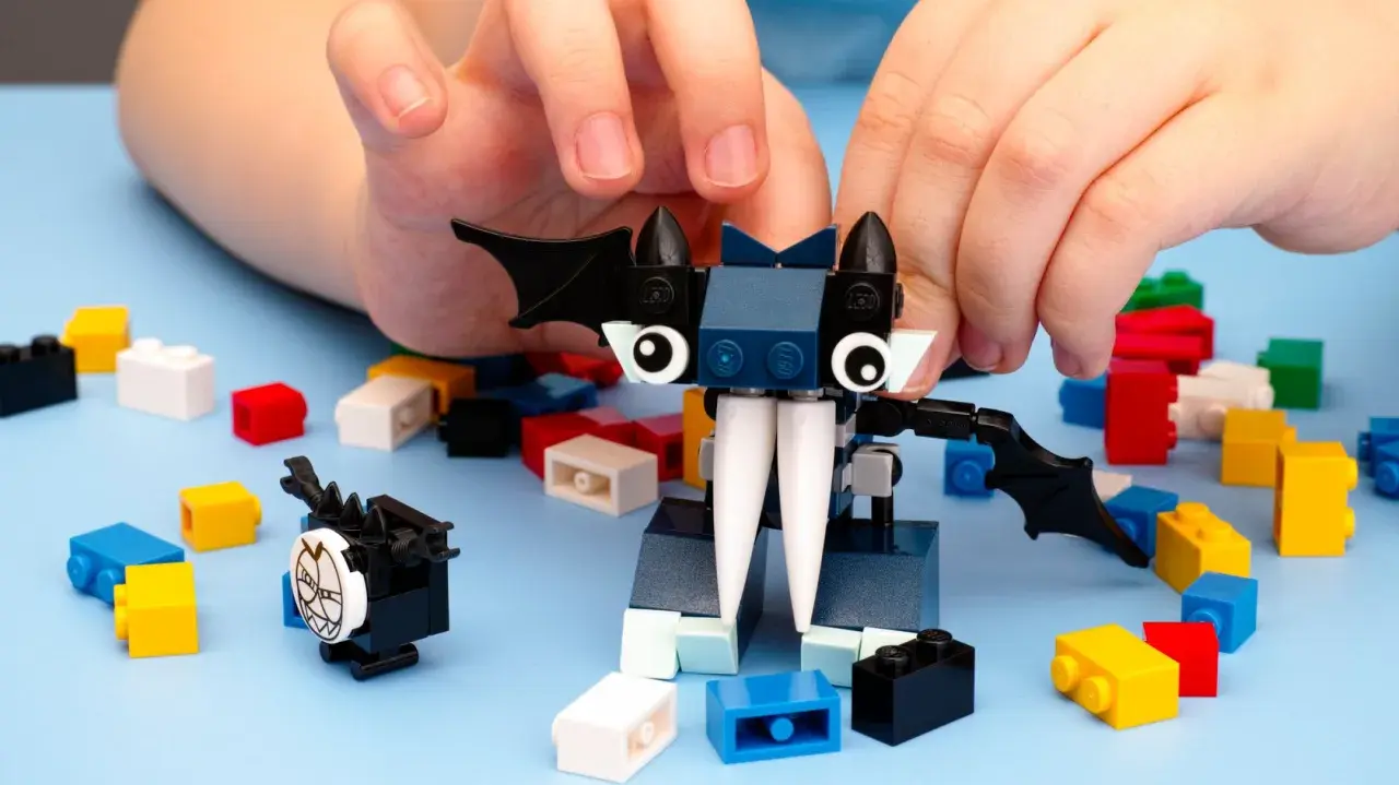 Kinderhände bauen mit bunten Klemmbausteinen einen Fledermaus-Charakter. Ein beliebter Klemmbaustein Hersteller ermöglicht kreativen Spielspaß.