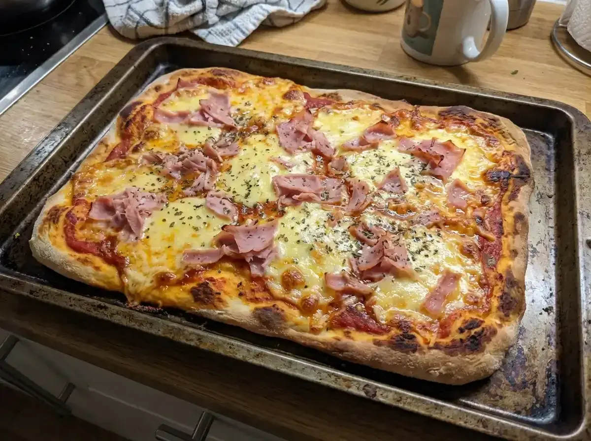En nybakad pinsa bianco med skinka och ost, redo att avnjutas.