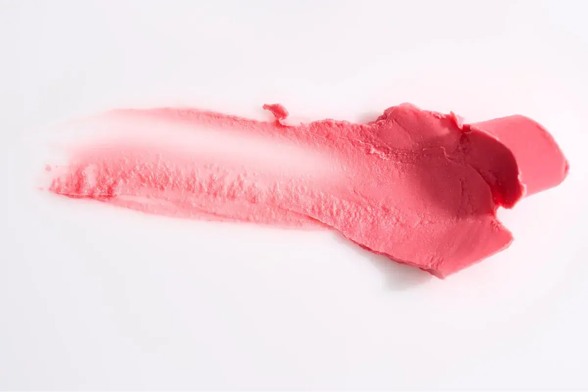 Smuga różowej pomadki, która może zawierać methylparaben, na białym tle.
